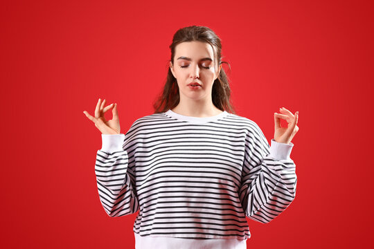 Meditating young woman on red background. Concept of self-control