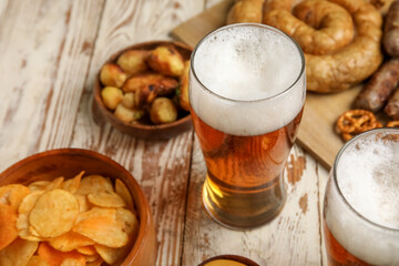 Glasses of cold beer and different snacks on light wooden background. Oktoberfest celebration