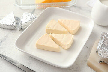 Plate with triangles of tasty processed cheese on light background, closeup