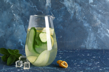 Jug of lemonade with cucumber and mint on blue background