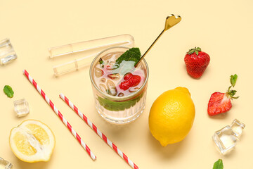 Glass of fresh lemonade with strawberry and lemon on beige background