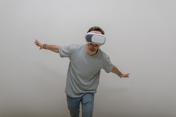 Futuristic man wearing virtual reality glasses interacts with the air in an isolated gray background.