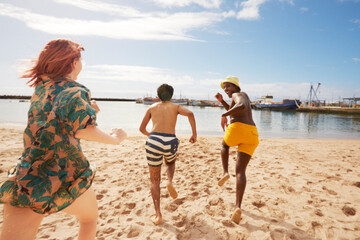 Young friends running into water on harbor beach while on summer vacation © Faces of Travel