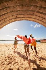Young friends running through tunnel into water on harbor beach while on summer holiday  © Faces of Travel