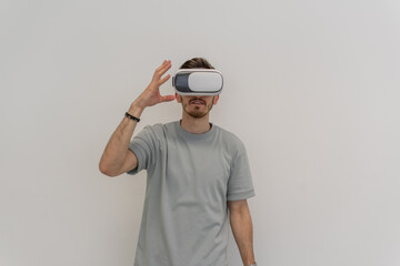 Futuristic man wearing virtual reality glasses interacts with the air in an isolated gray...