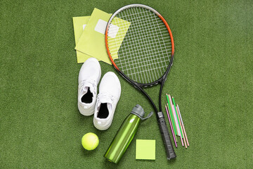 Sneakers with bottle of water, tennis ball, racket and different stationery on color background