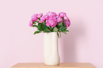 Vase of pink peonies on shelving unit near color wall