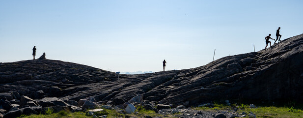 panorama sur un colline rochause sur laquelle grimpent ciinq silhouettes