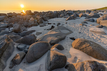 soleil de minuit sur une plage de rochers ronds