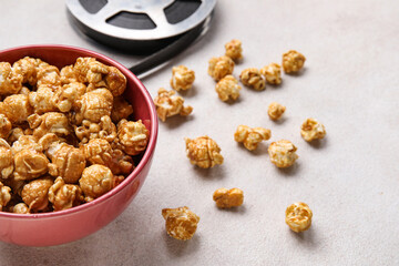 Bowl with tasty popcorn and film reel on white background