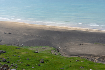 paysage d'une plage sauvage avec une eau bleue pale et pentes vertes 