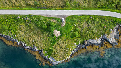 vue aérienne sur des fonds marins bleues et une route au milieu d'une végétation verte 