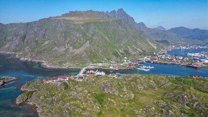 un village de maisons nordiques et rouges entre deux  îles montagnes reliées par une route 