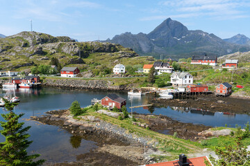 Des maisons rouges et blanches dispersées le long des rivages de l'île avec des montagnes en arrière plan 