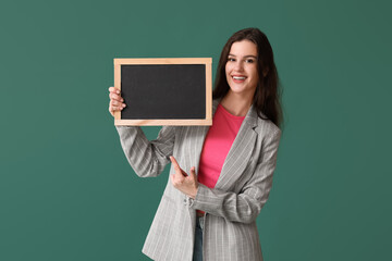 Female teacher pointing at chalkboard on green background