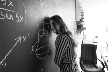 Stressed female Math teacher near blackboard in classroom