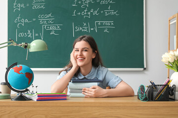 Female teacher sitting at table in classroom