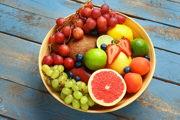 Bowl with different fresh fruits on blue wooden background