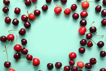 Frame made of sweet cherries on turquoise background