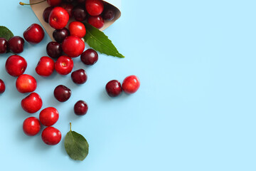 Newspaper with sweet cherries on blue background