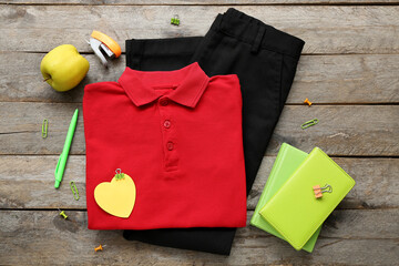 Different stationery with stylish school uniform and fresh apple on brown wooden background
