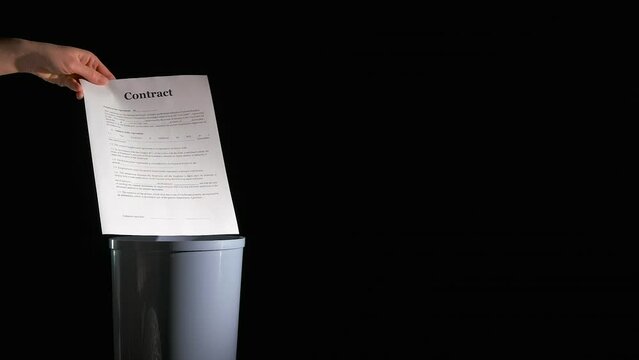 Useless business documents on black background. A woman throw the useless contracts documents into waste bin on the black background.