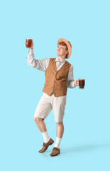 Young man in traditional German clothes with beer dancing on blue background