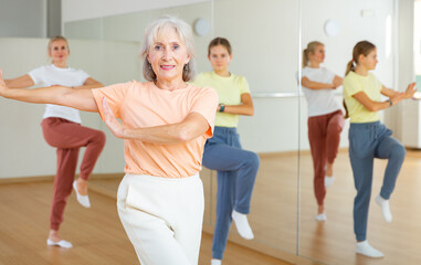 Senior woman performing contemporary dance during group training in studio.