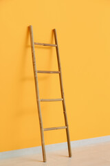 Wooden ladder near orange wall in room