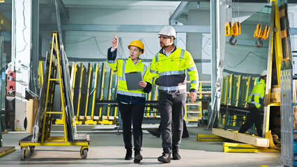 Male and female colleagues talking and planning work whilw walking at production factory. Work with...
