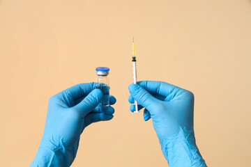 Doctor with vaccine and syringe on beige background