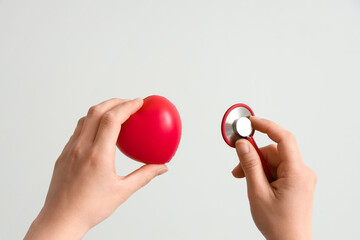 Doctor with plastic heart on light background