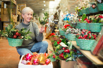 Caucasian aged woman choosing christmas ornaments in store.