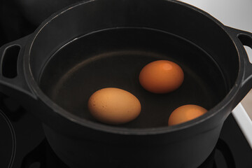 Chicken eggs boiling in cooking pot, closeup