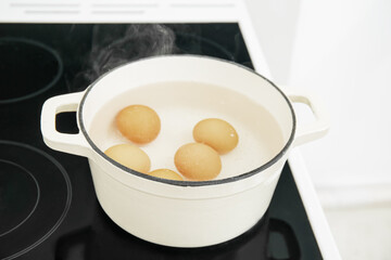 Chicken eggs boiling in cooking pot on stove
