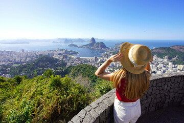 Aerial view of stylish girl holding hat on Rio de Janeiro viewpoint with Guanabara Bay, Rio de Janeiro, Brazil