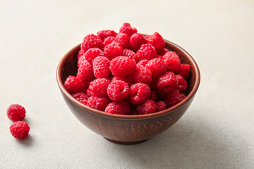 Bowl with fresh raspberries on white background