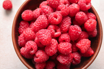 Bowl with fresh raspberries on white background