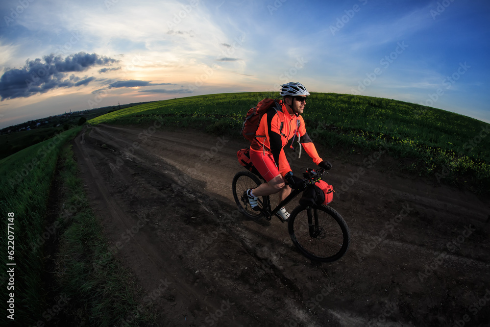 Sticker man on mountain bike rides on the trail on a beautiful sunset. wide view