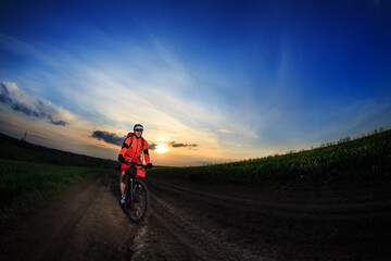 Obraz premium Man on mountain bike rides on the trail on a beautiful sunset. Wide view