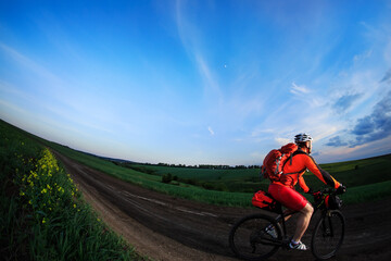 Fototapeta na wymiar Man on mountain bike rides on the trail on a beautiful sunset. Wide view