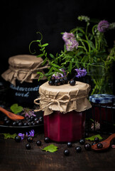 Jar of delicious homemade black currant curd (jam) on dark background