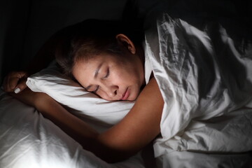 young woman sleeping on side in her bed at night. Beautiful girl sleeping with closed eyes.