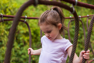 Adorable little girl having fun on a rope playground in the park