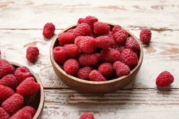 Bowls with fresh raspberry on light wooden background, closeup
