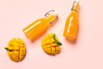 Bottles of fresh mango juice on pink background