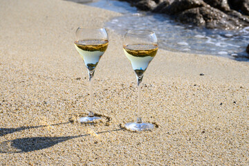 Summer time in Provence, two glasses of cold champagne cremant sparkling wine on sandy beach near Saint-Tropez in sunny day, Var department, France