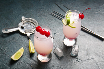 Glasses of tasty cocktail with maraschino cherries on grey background