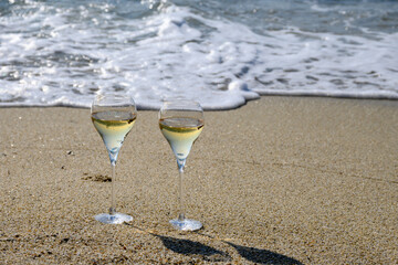 Summer time in Provence, two glasses of cold champagne cremant sparkling wine on sandy beach near Saint-Tropez in sunny day, Var department, France