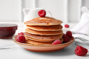 Plate of tasty pancakes with raspberries on table